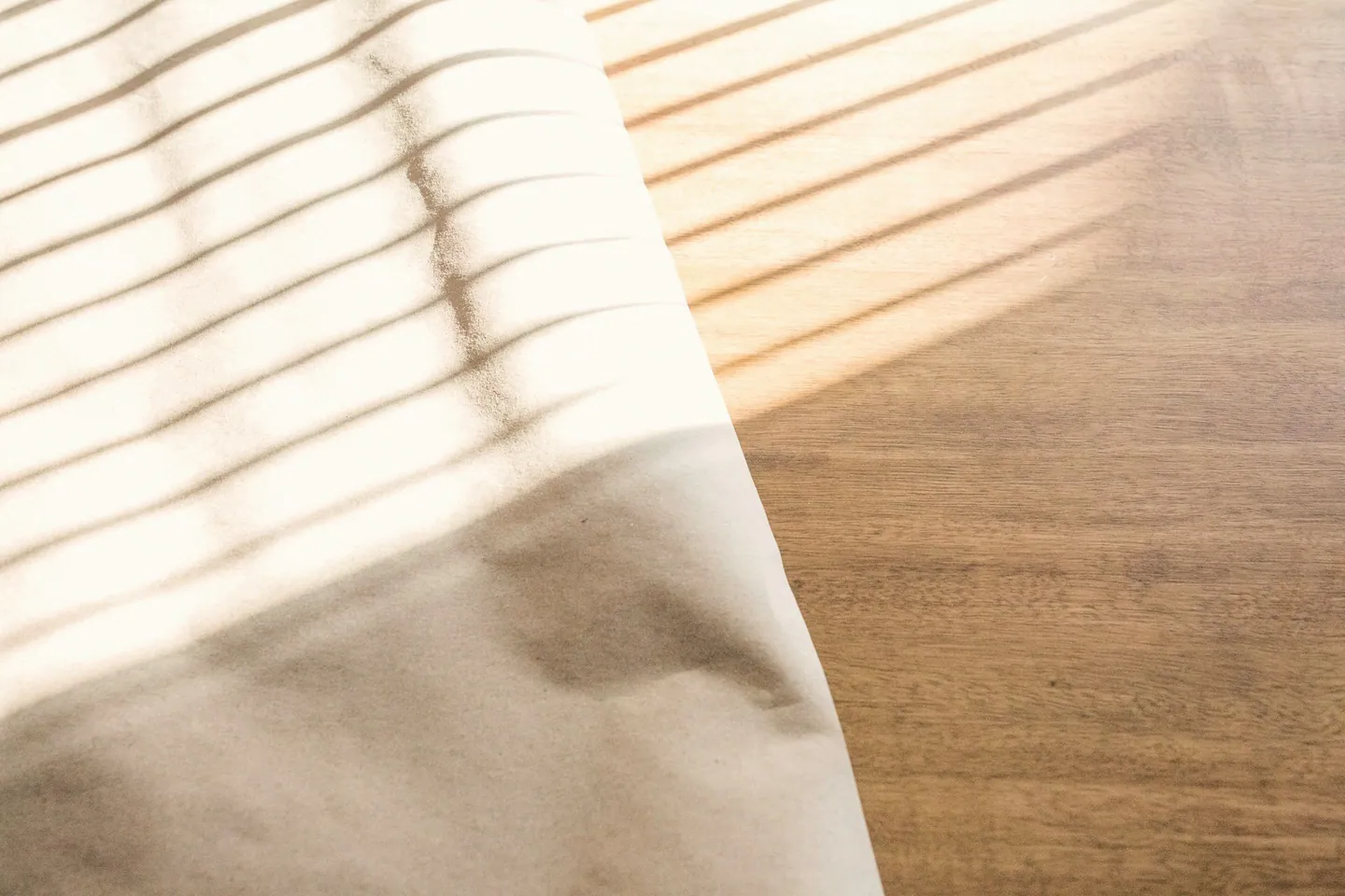 Lumière de fin de matinée entrant de côté sur une table en bois et du papier